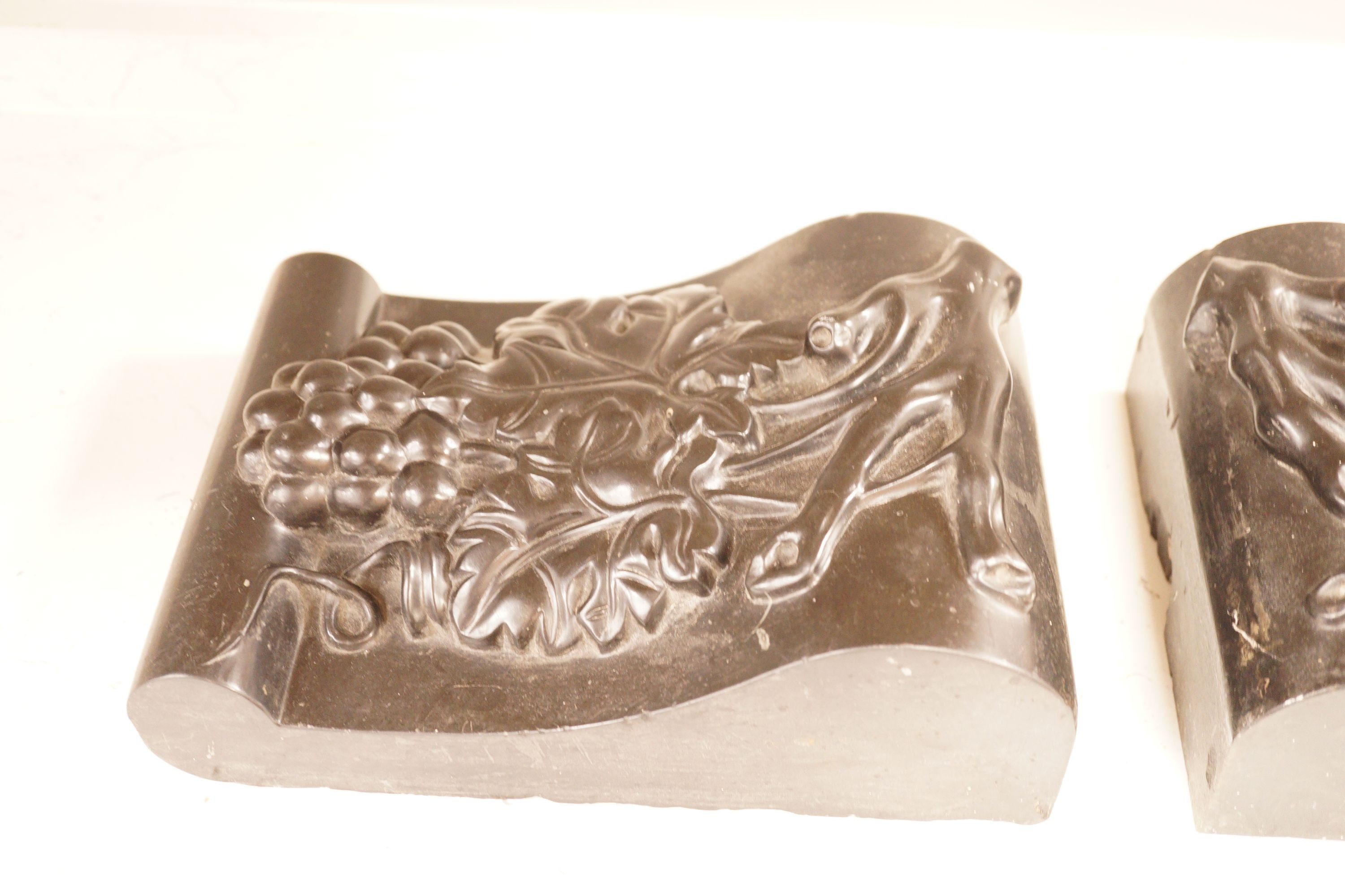 A pair of carved black marble corbels, fruiting vines, 24x17cm